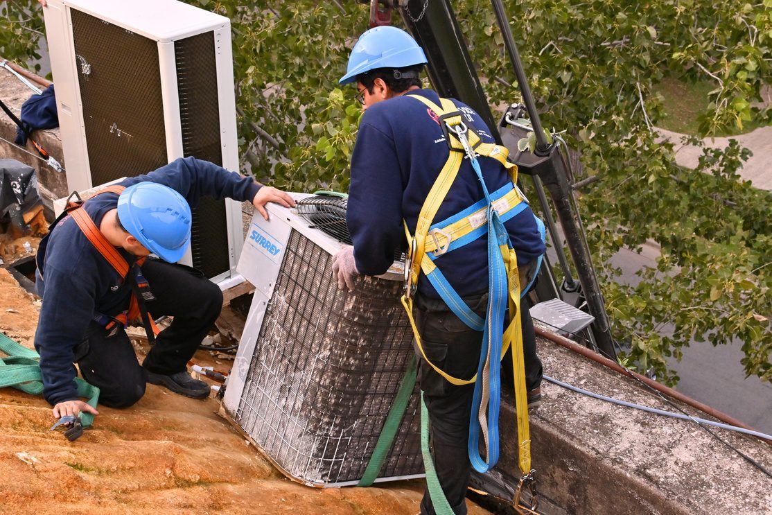 Técnicos de Service Segui instalando un equipo de climatización en altura